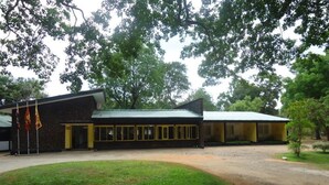 A building with a green roof, a covered entrance, and a grassy area in front.