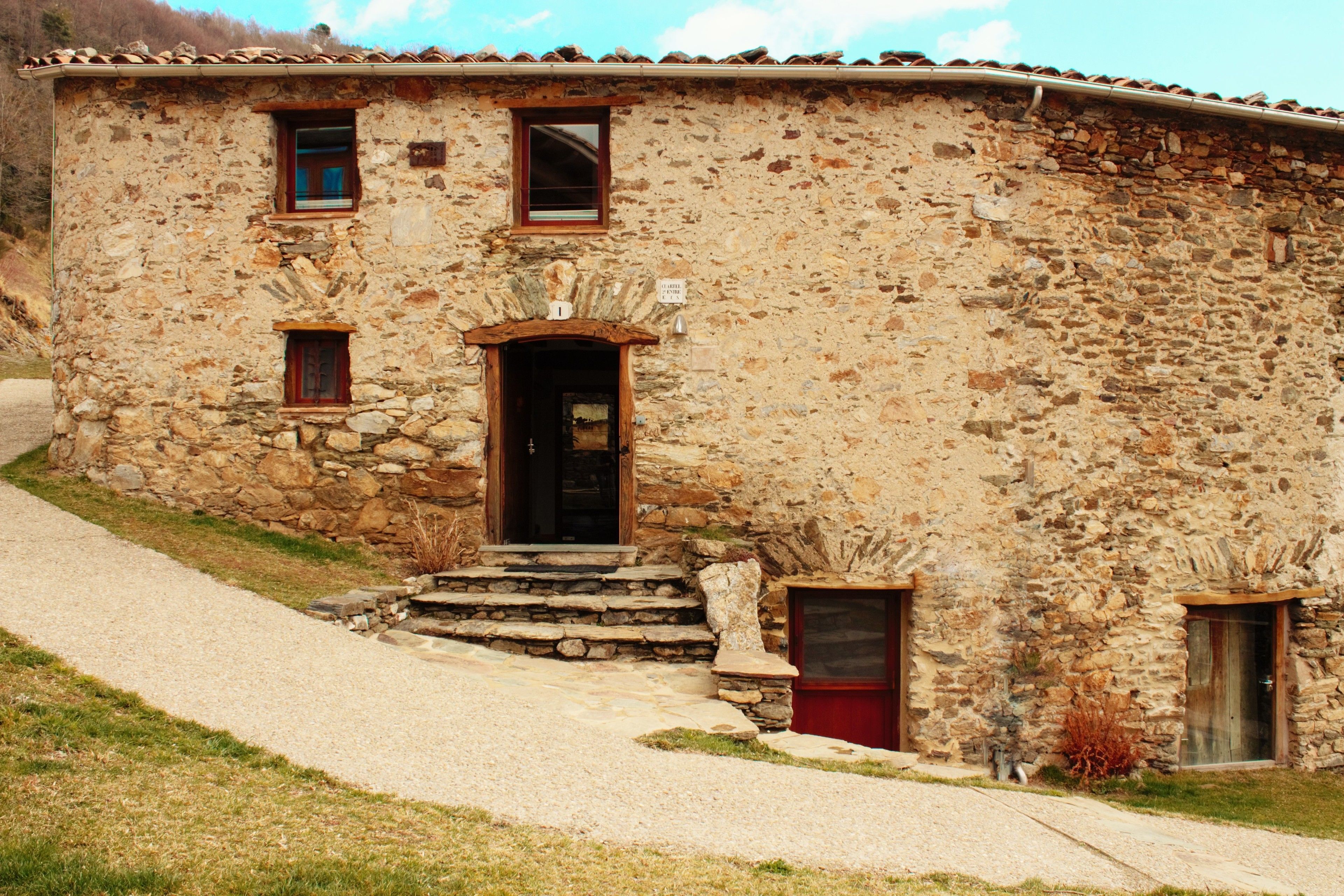 Un edificio de piedra rústico con una entrada tradicional, un pequeño porche y una ventana visible.