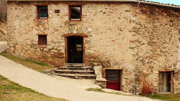 Un edificio de piedra rústico con una entrada tradicional, un pequeño porche y una ventana visible.