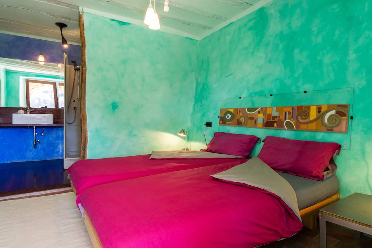 Un dormitorio con dos camas, un baño y una mesita.