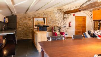 A rustic interior with a stone wall, wooden furniture, and a fireplace.