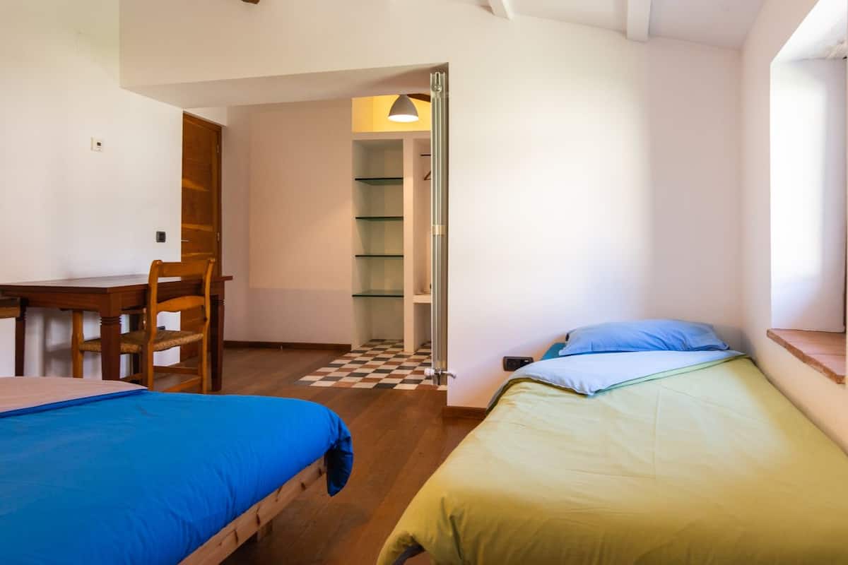 Una habitación tipo dormitorio con dos camas, un escritorio y una silla.