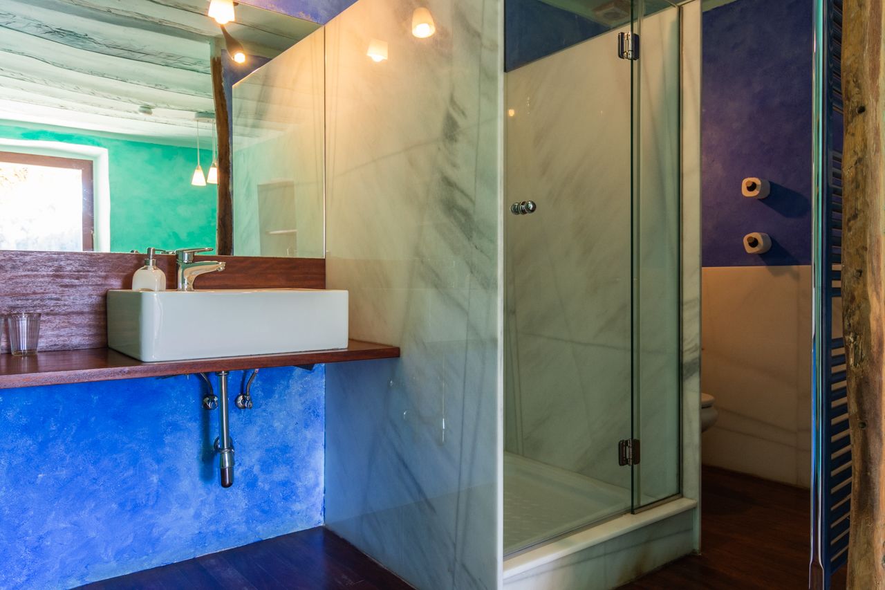 A bathroom with a marble sink, a glass shower enclosure, and a wooden vanity.