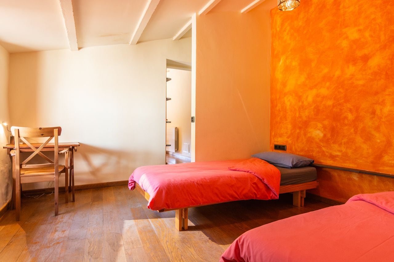 Een kamer met twee bedden, een houten stoel en een houten tafel.
