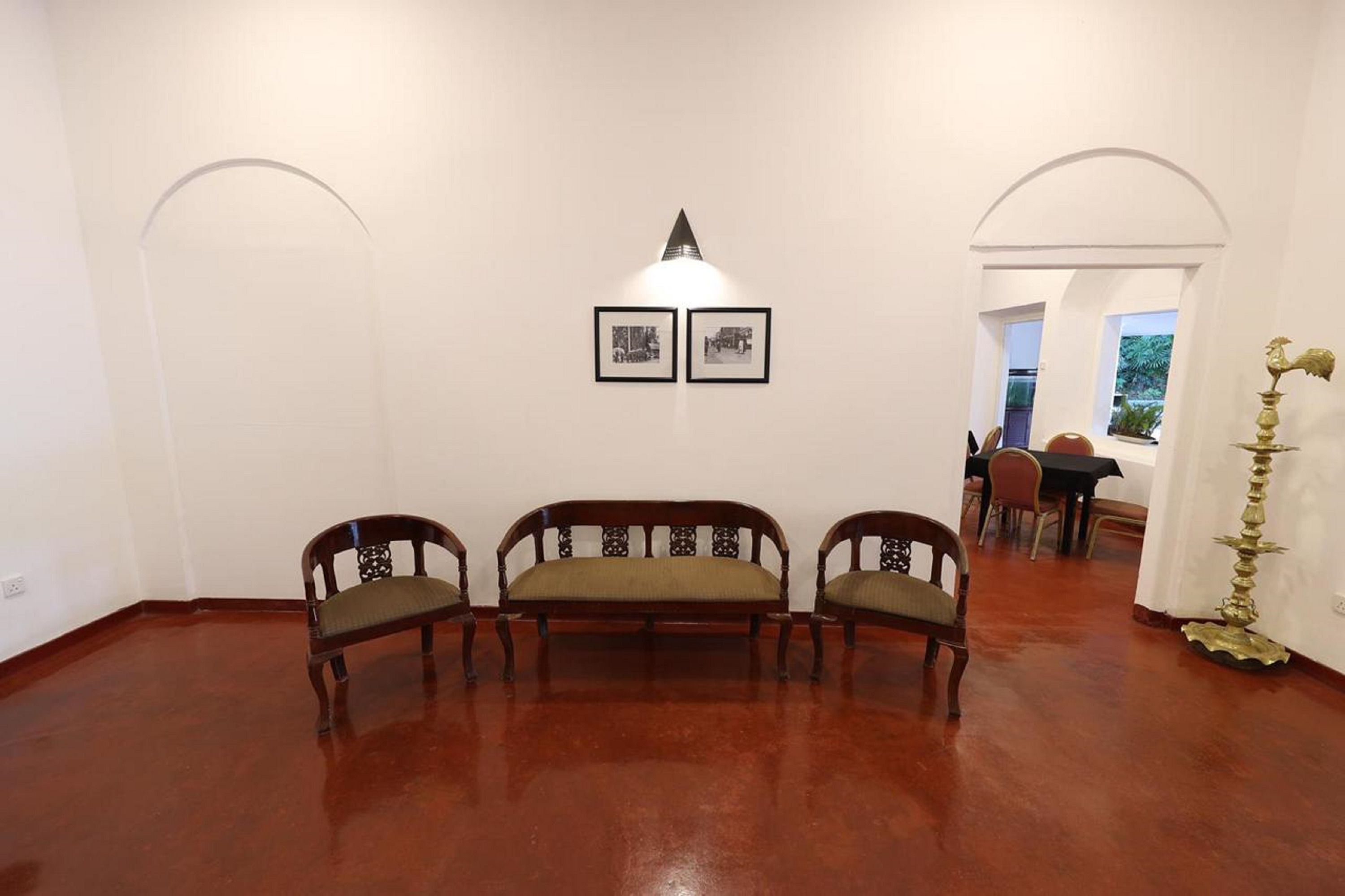 A room with a wooden bench, two chairs, a table, and a lamp.