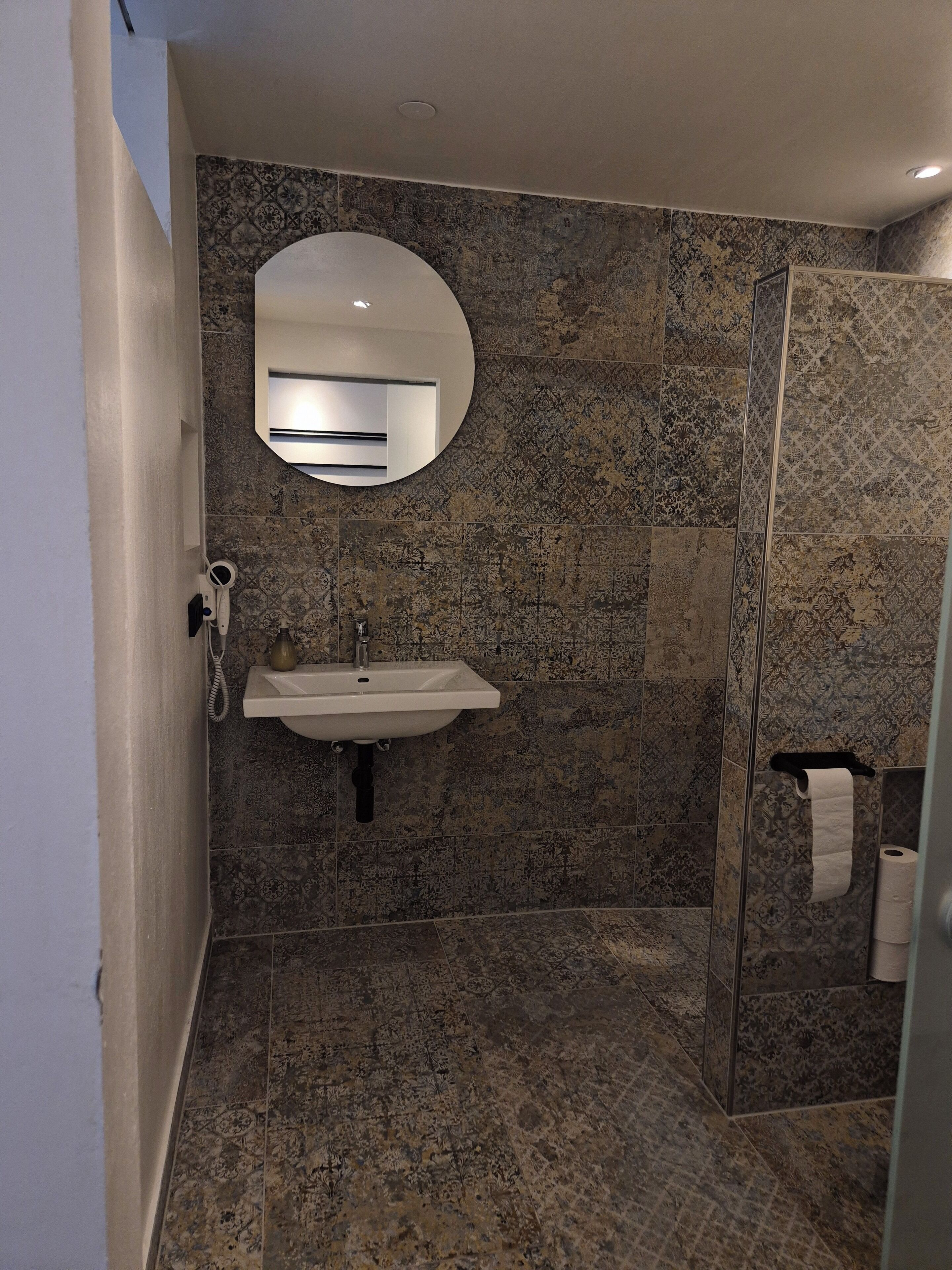 Un baño con lavamanos, espejo y ducha.