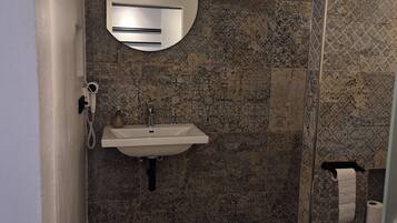 Un baño con lavamanos, espejo y ducha.