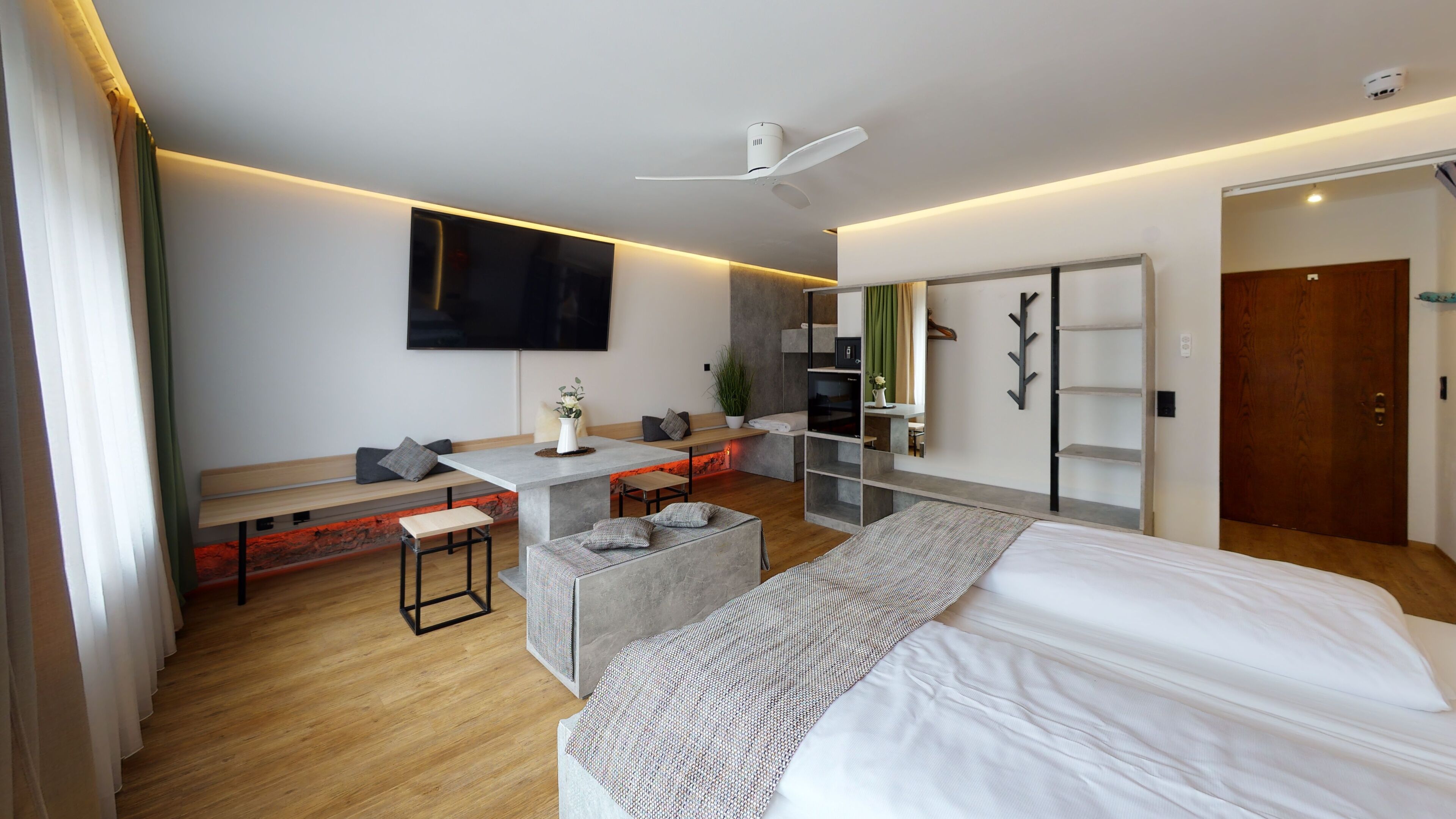 Une chambre d’hôtel moderne équipée d’un lit, d’un bureau, d’une banquette et d’un coin salon.