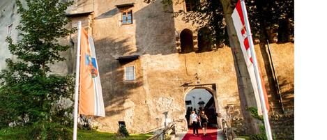 A historic building with a red carpet leading to an entrance, surrounded by trees and flags.