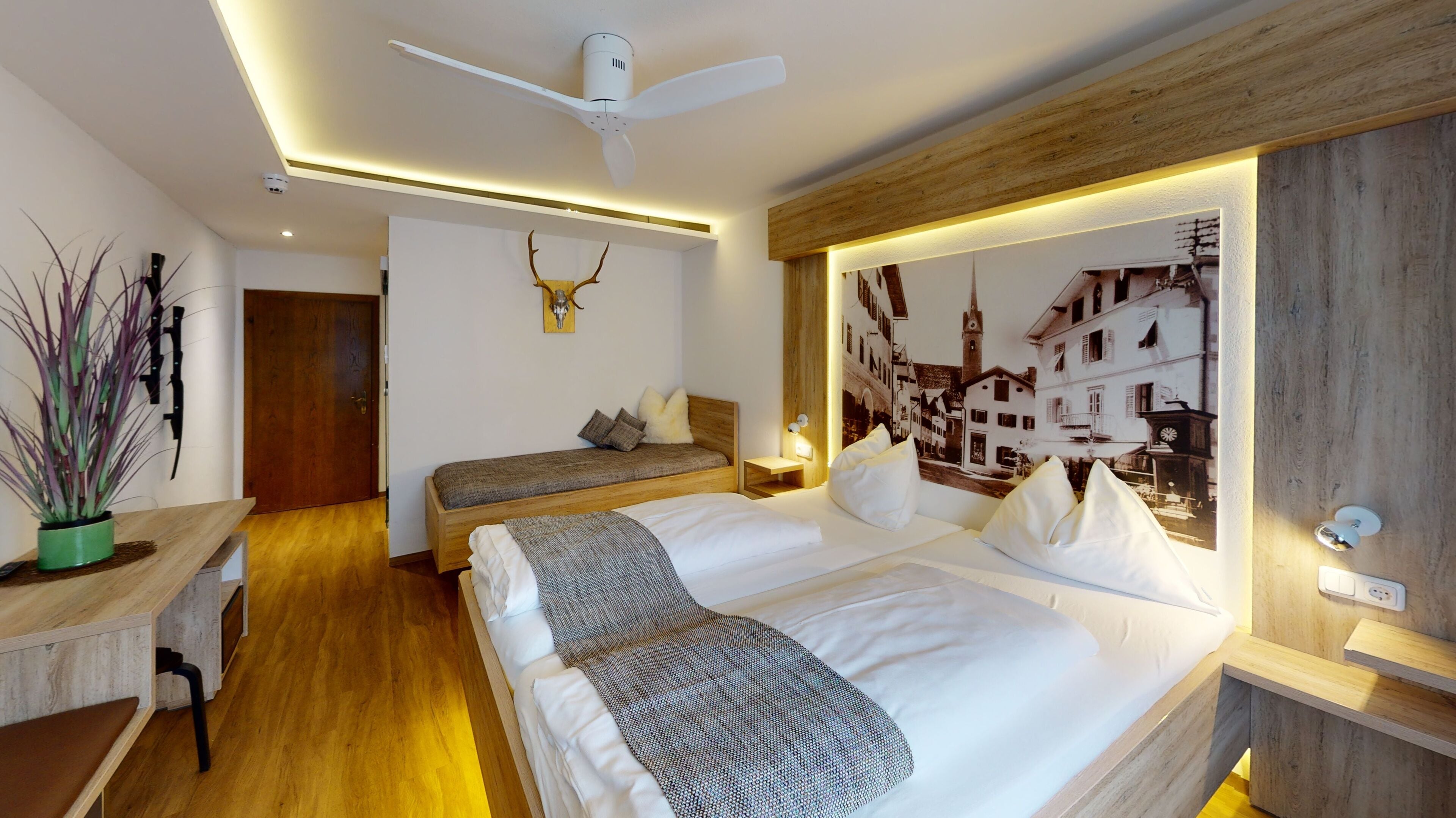 Una habitación de hotel moderna con una cama grande, un escritorio y un ventilador de techo.