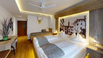 A modern hotel room with a large bed, a desk, and a ceiling fan.
