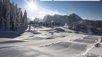 Ein Skigebiet mit blauem Himmel, verschneiten Pisten und einem Shuttle-Service für Hotelgäste.