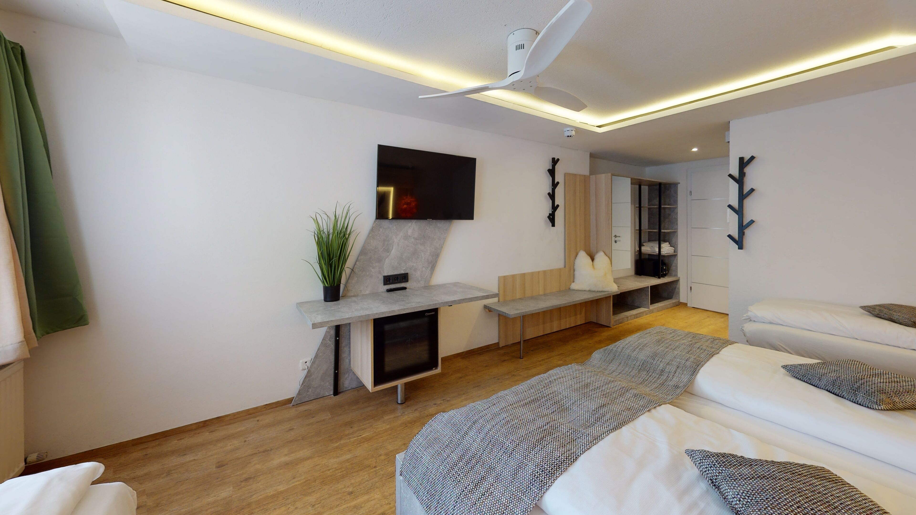 Un salon moderne avec un canapé, un téléviseur fixé au mur, une cheminée et un ventilateur de plafond.
