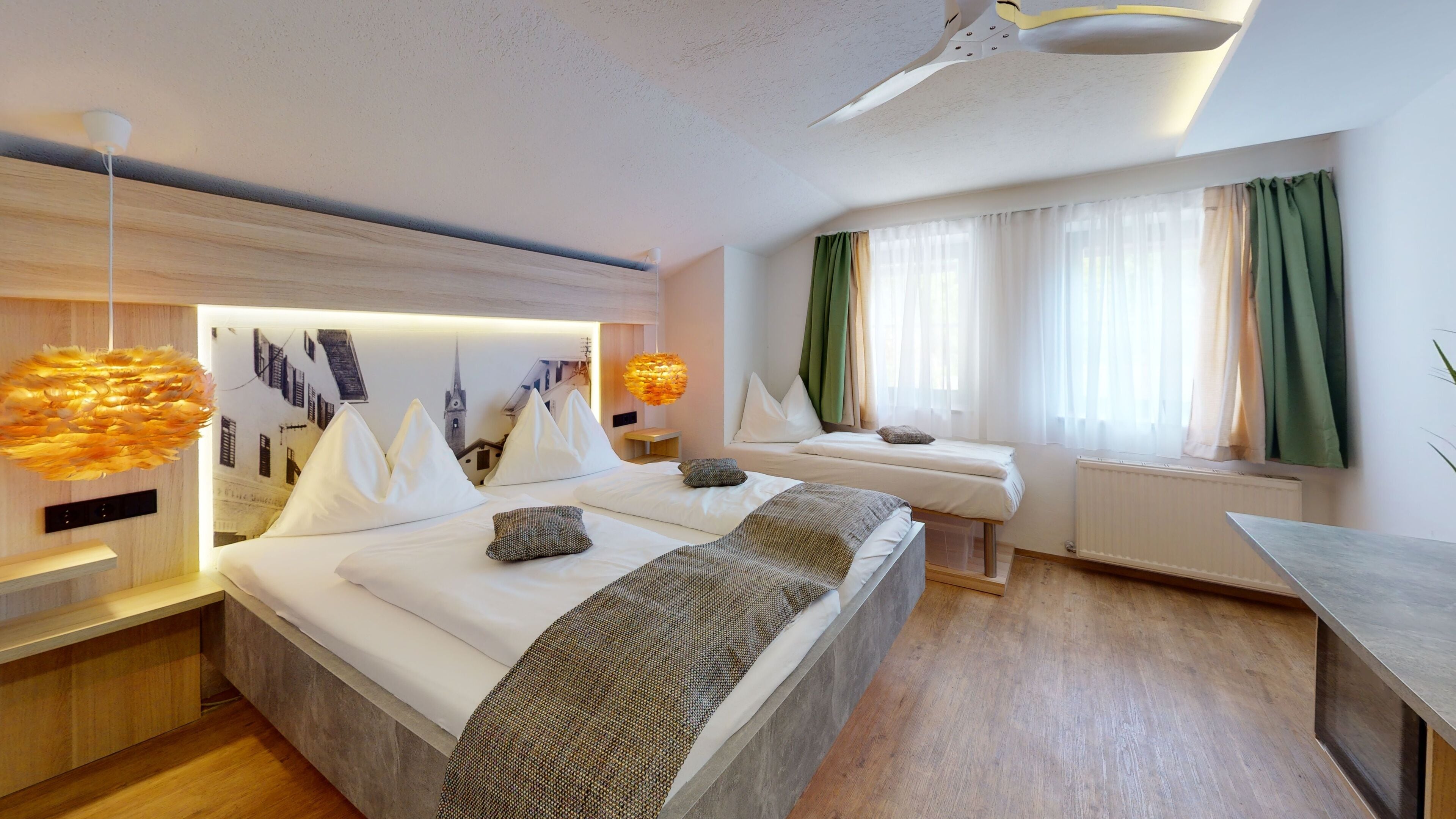 Habitación de hotel moderna con una cama grande, dos mesitas de noche, un escritorio y vistas de la ciudad a través del ventanal.