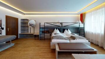 Un dormitorio moderno con una cama alta, una mesita de noche, una silla, un espejo y una ventana con cortinas.