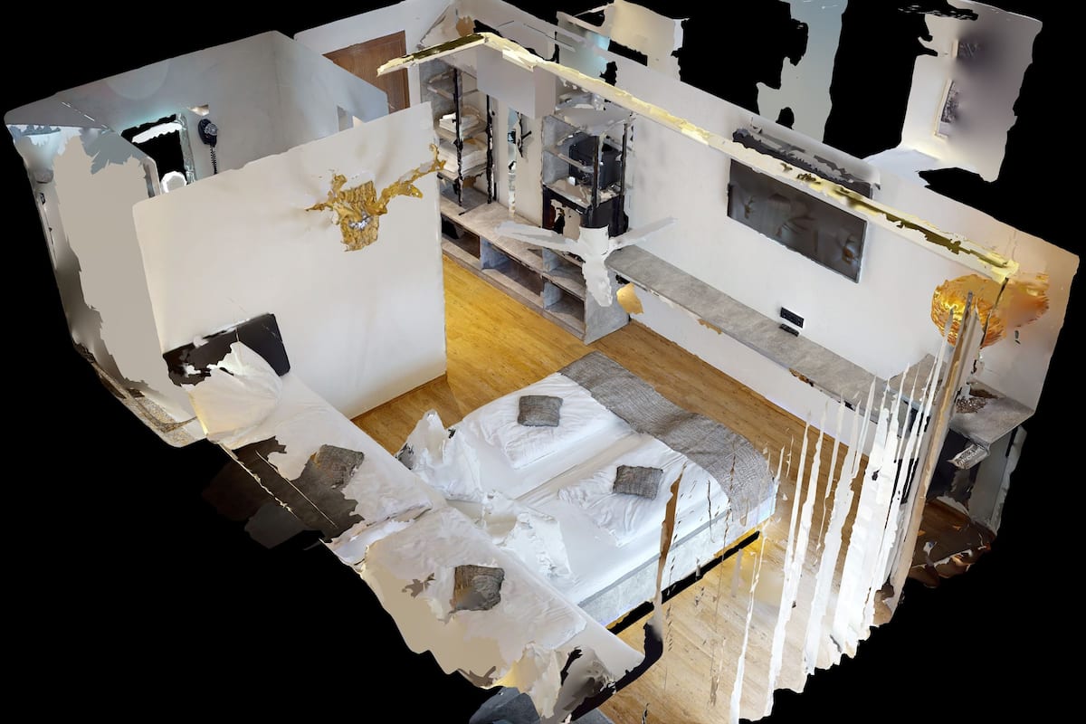 A 3D model of a hotel room with a bed, a desk, a chair, and a wardrobe.