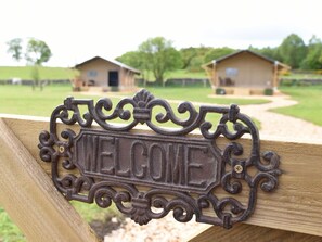 Een 'WELKOM'-bord van ijzerhangers op een houten hek.
