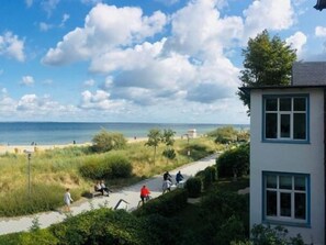 A coastal path with people walking and cycling, leading to a beach. - Kleines Strandhotel (Timmendorfer Strand)