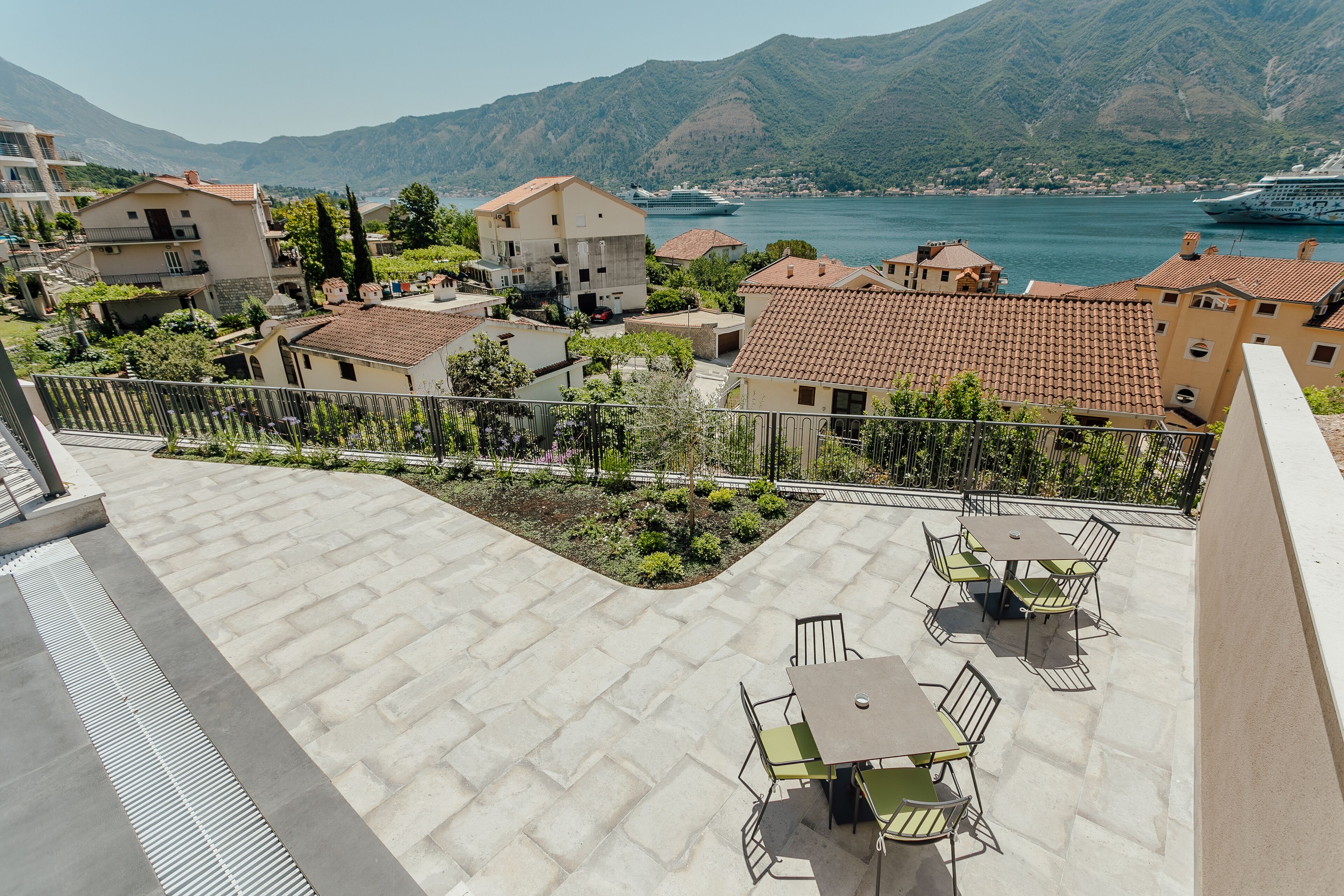 A terrace with outdoor seating and a view of a lake and mountains.
