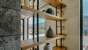 Un intérieur moderne avec des étagères en bois où sont exposés des objets décoratifs, et une vue sur l’extérieur.