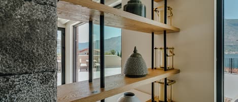 Un interior moderno con estantes de madera que exhiben objetos decorativos y vistas al exterior.