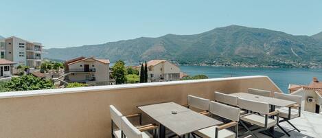 A terrace with outdoor seating and a view of a lake and mountains.