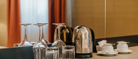 Habitación de hotel con minibar que incluye copas de vino, hervidor de agua y cafetera.