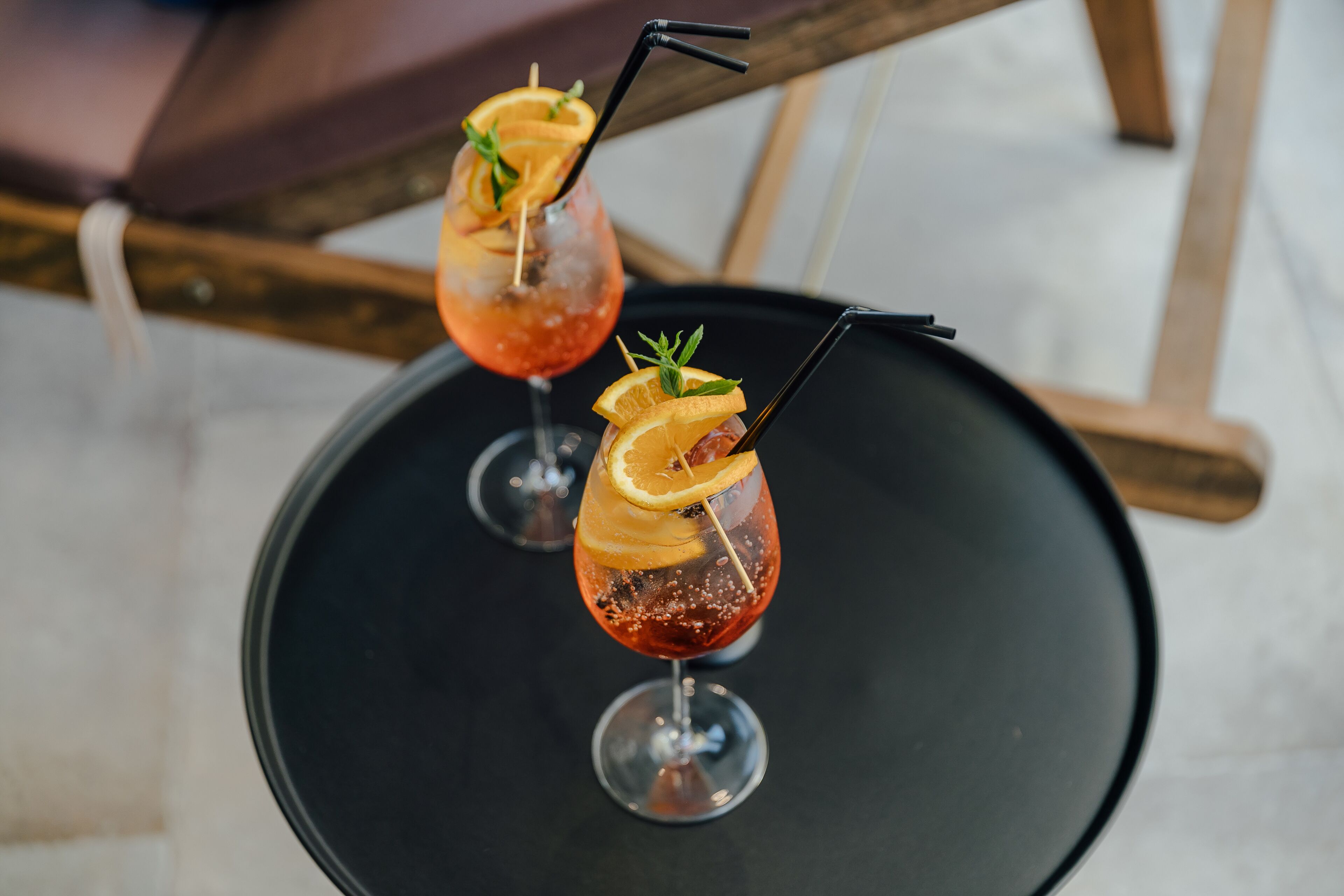 Dois cocktails com guarnições sobre uma bandeja preta.