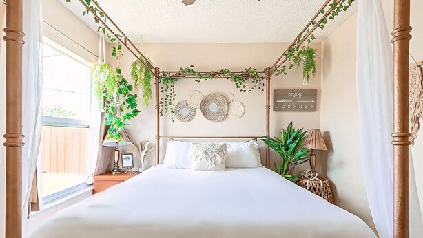Quarto com uma cama grande, cabeceira de madeira e vista para o exterior.