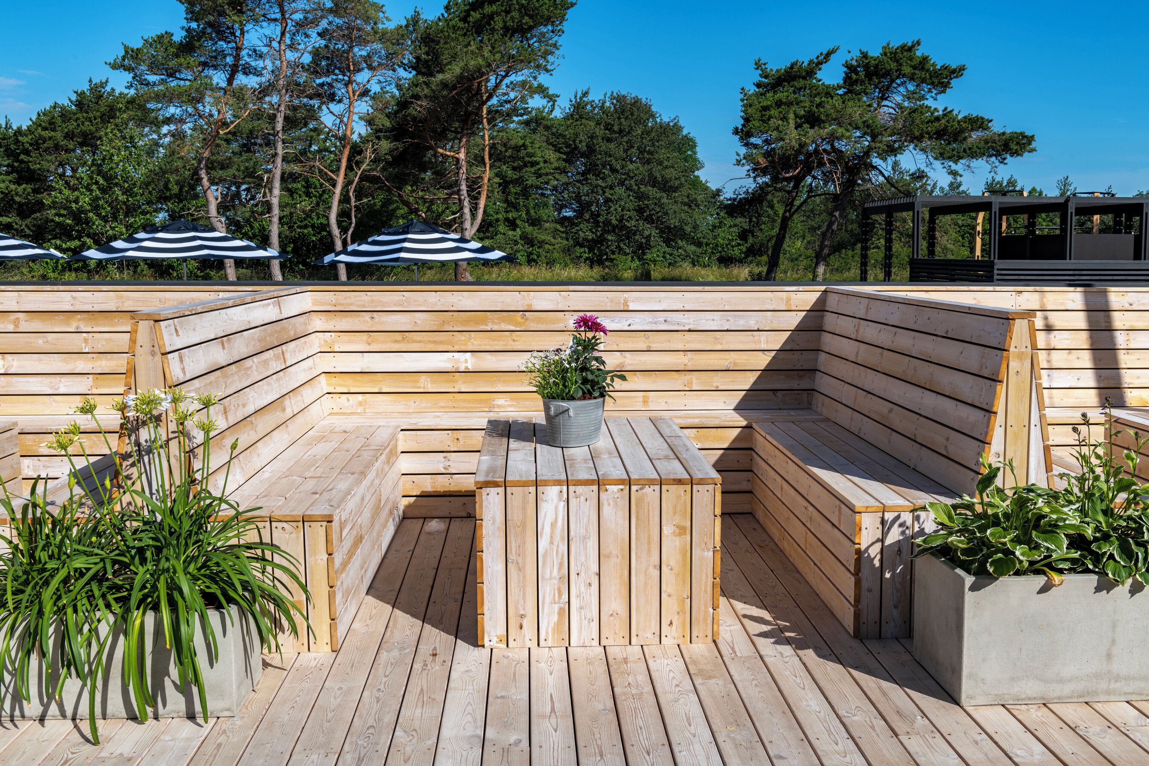 Una terraza de madera con asientos integrados y jardineras.