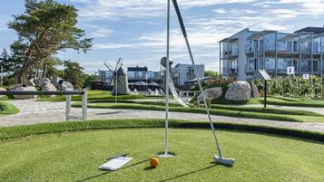 A well-maintained golf course with a putting green, a flagstick, and a golf ball.