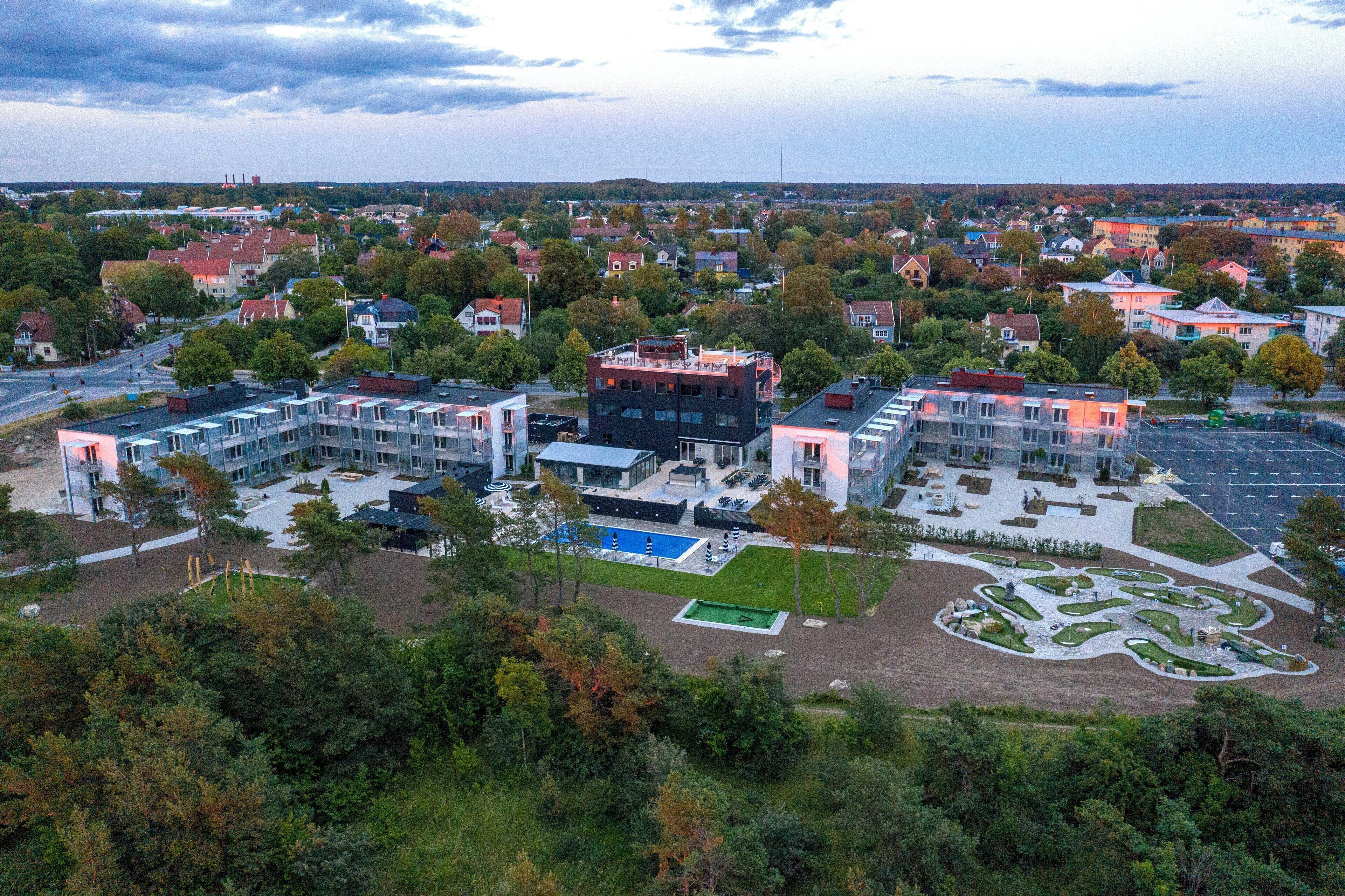 Un moderno complejo arquitectónico con varias unidades residenciales, una piscina y jardines ajardinados.