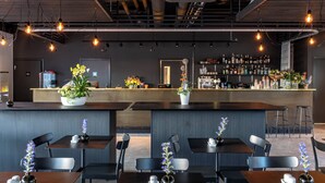 Un espace bar moderne, doté d’un comptoir, de sièges et d’un assortiment de bouteilles.