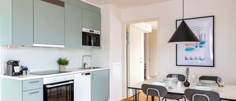 A modern kitchen with light blue cabinets, a built-in oven, and a dining area with a table set for four.