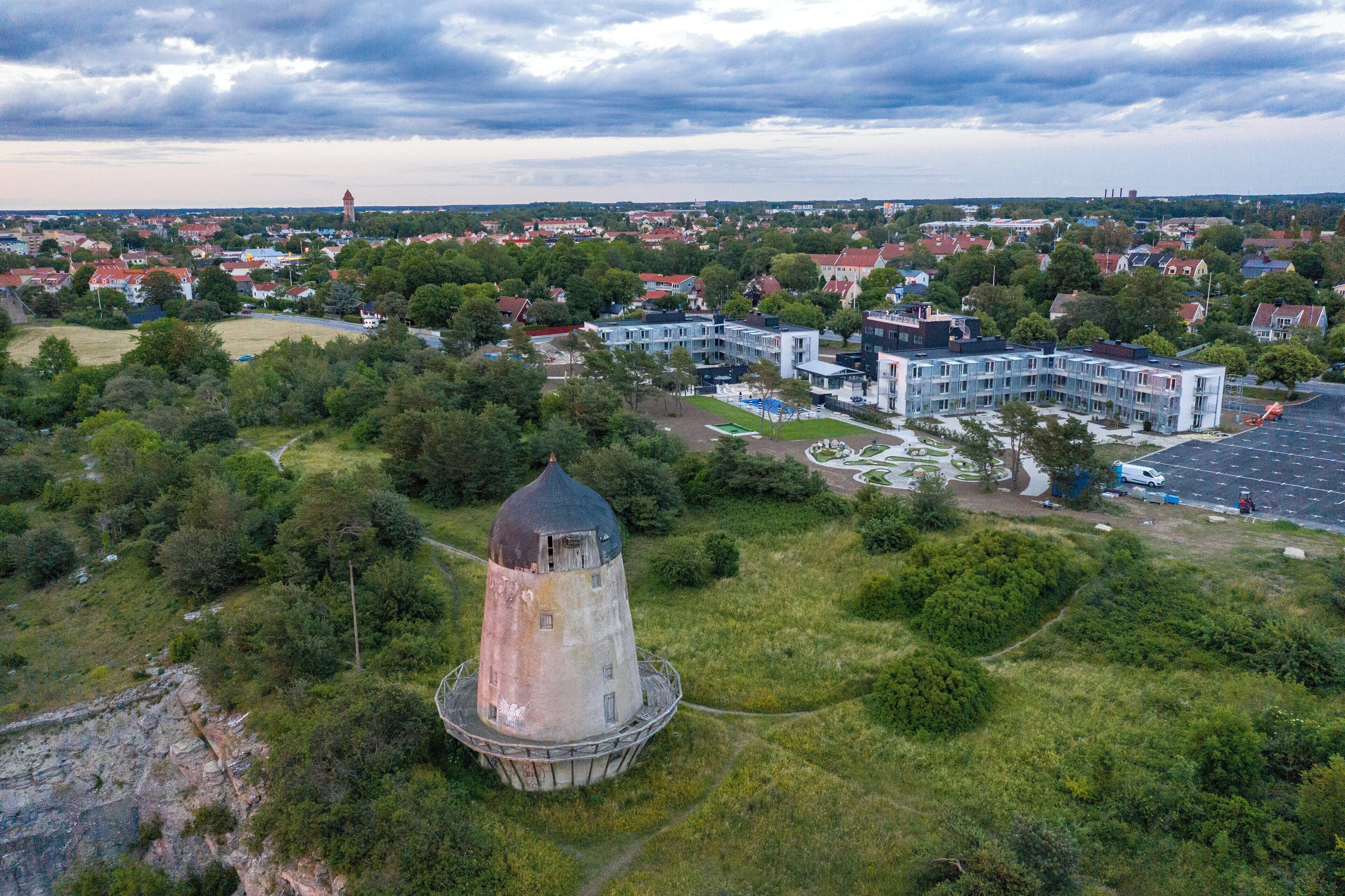 A large, historic water tower surrounded by lush greenery and modern buildings.