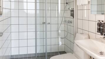 A modern bathroom with a glass-enclosed shower, a white toilet, and a sink with a mirror above it.