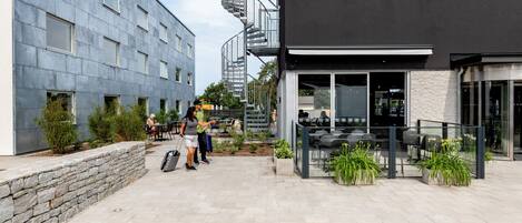 A modern building with a stone facade, outdoor seating area, and a spiral staircase.