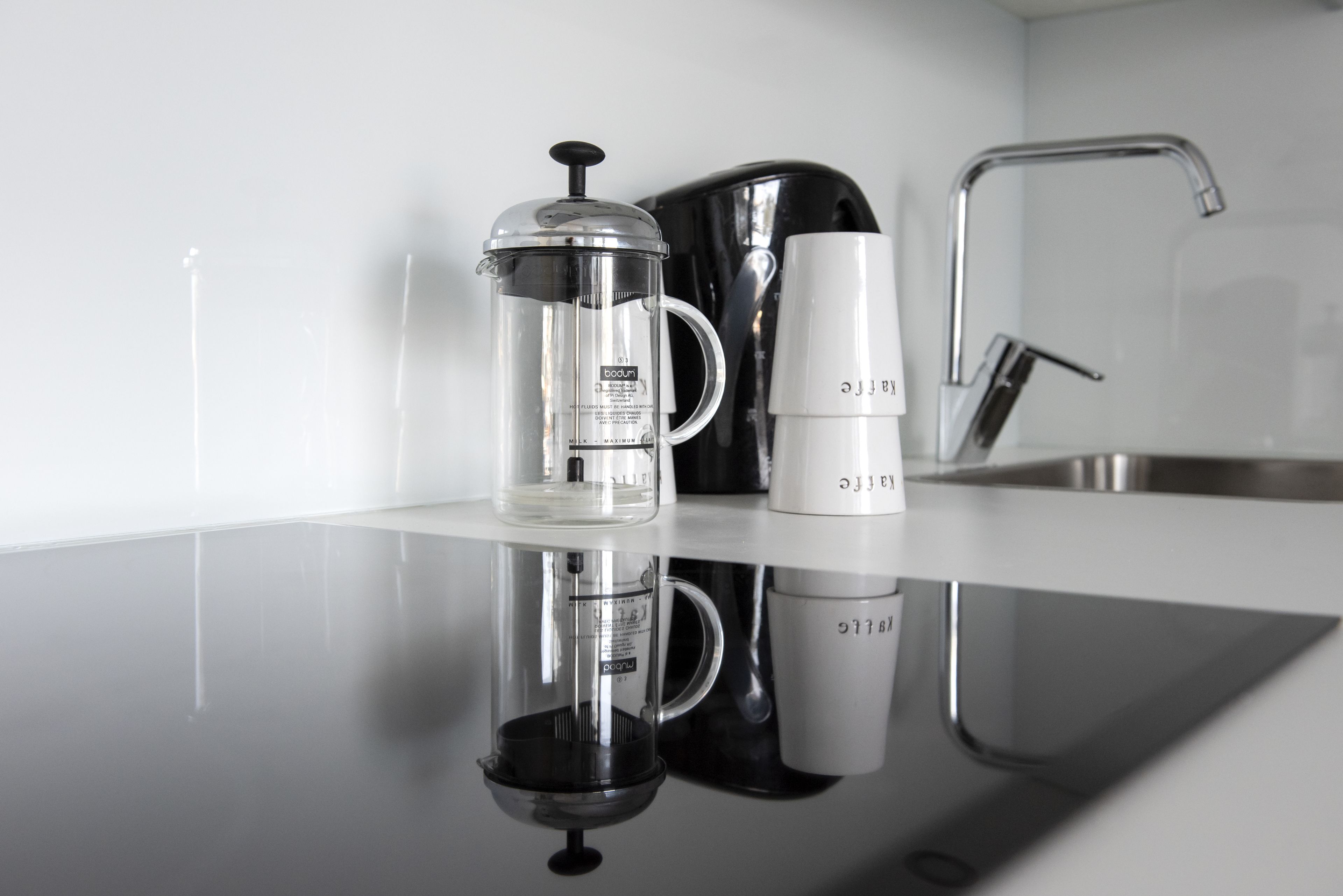 A kitchen counter with a coffee maker, a French press, and a mug.