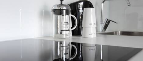 A kitchen counter with a coffee maker, a French press, and a mug.