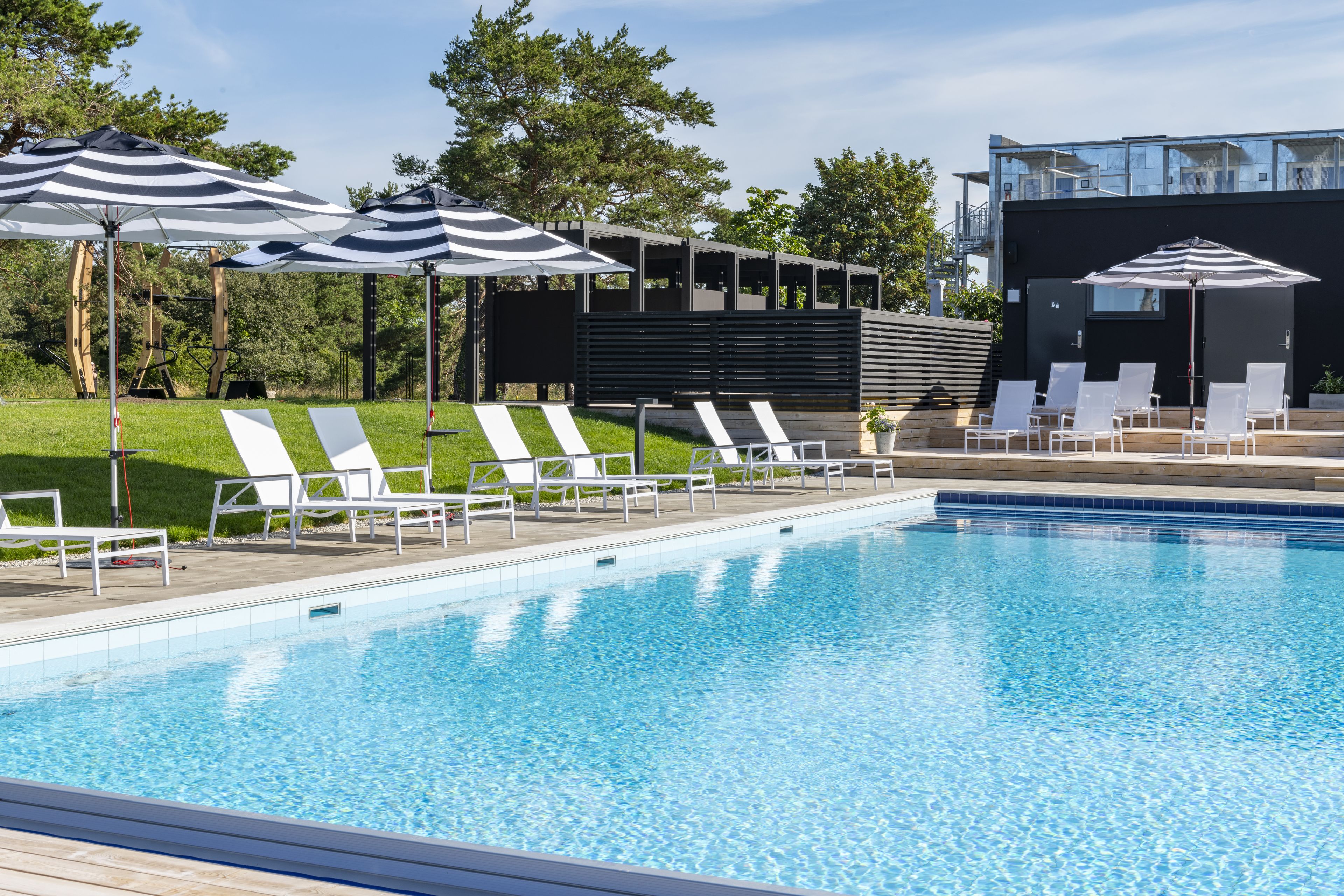 A swimming pool with lounge chairs and striped umbrellas.
