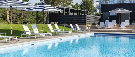 A swimming pool with lounge chairs and striped umbrellas.