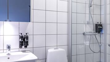 A modern bathroom with a white sink, toilet, and glass-enclosed shower.