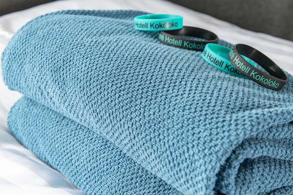 A blue towel with a Hotel Kokolo logo and a black wristband with the same logo. - First Hotel Kokoloko (Visby)