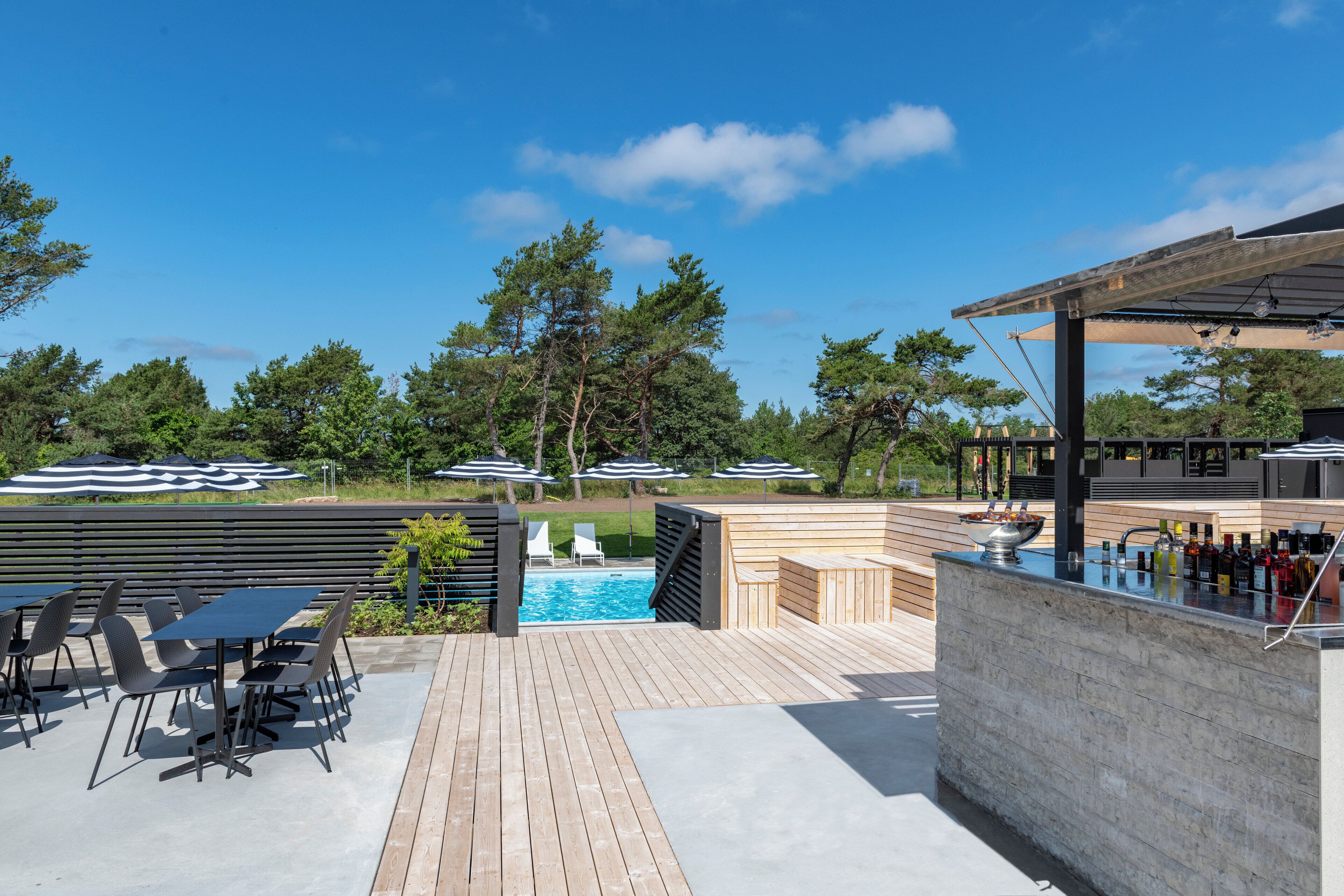 A patio with outdoor seating, a pool, and a bar area.