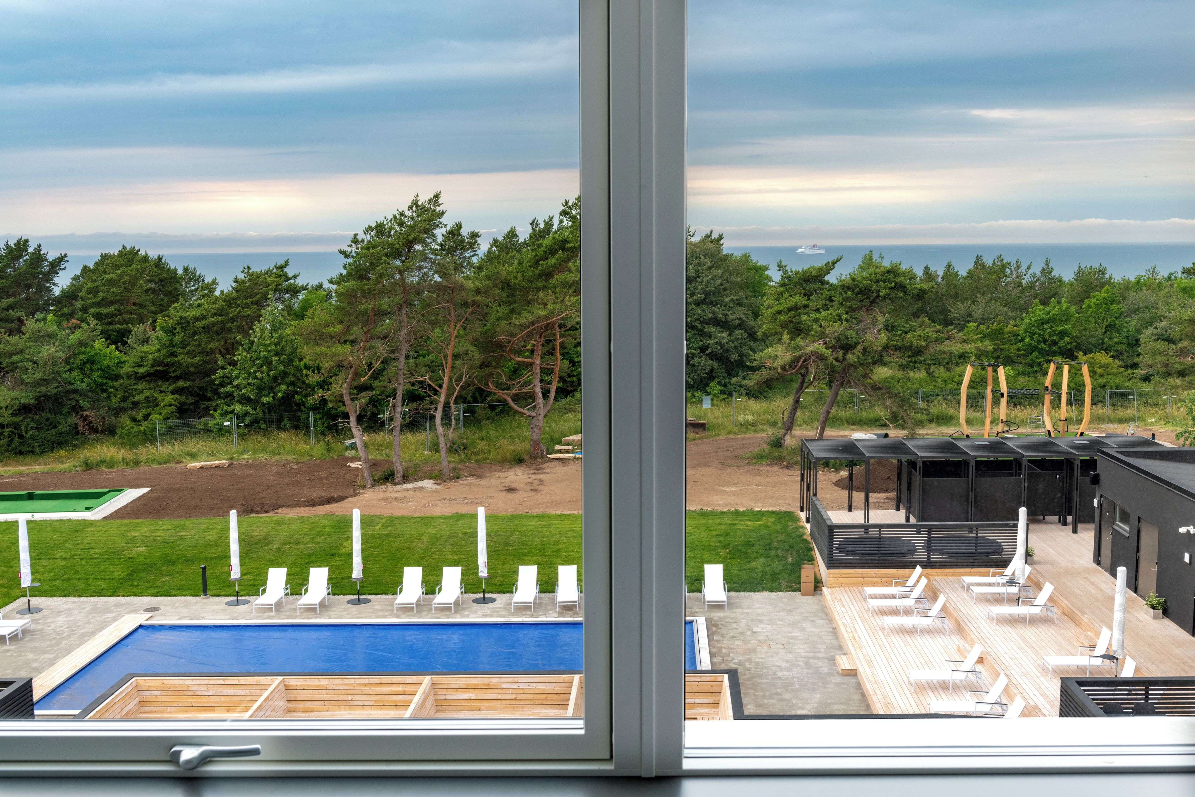 Ein moderner Poolbereich mit Liegestühlen und Blick auf das Meer.