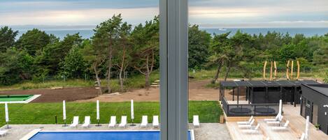 Un área de piscina moderna con sillones reclinables y vistas al océano.