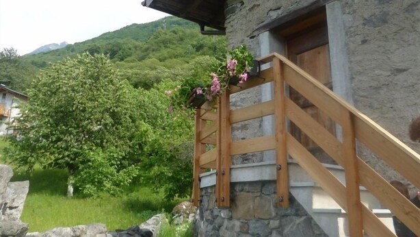 Un edificio de piedra con una escalera y baranda de madera.