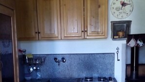 Una cocina con armarios de madera, una estufa y un reloj en la pared.