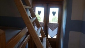 Una escalera de madera en una habitación con un ventanal que tiene formas de corazón.