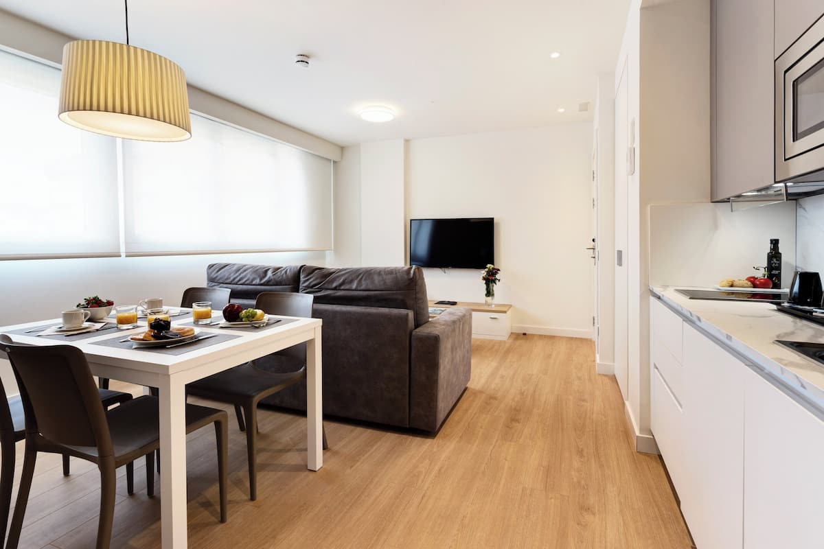 A modern living space with a dining area, sofa, and kitchen.